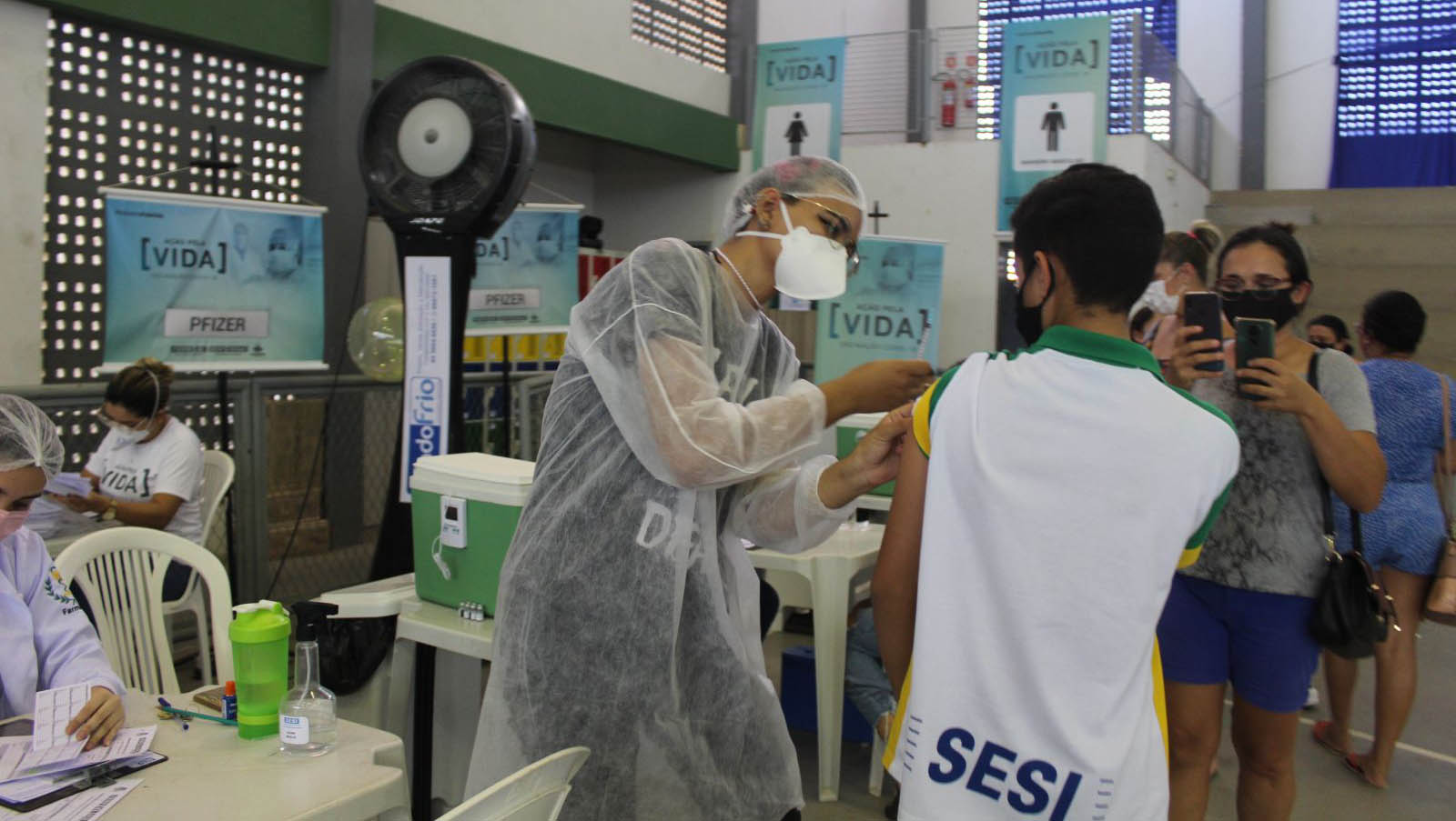   Mossoró segue vacinando adolescentes e amplia público-alvo para jovens de 15 anos+. A vacinação para esta faixa etária começou nesta sexta-feira (17) e acontece no Ginásio do Sesi. Amanhã a imunização começa às 8h e vai até as 16h nos ginásios do Sesi e Pedro Ciarlini. No domingo, a vacinação acontecerá apenas no Ginásio de Esporte Pedro Ciarlini, Centro, também das 8h às 19h.