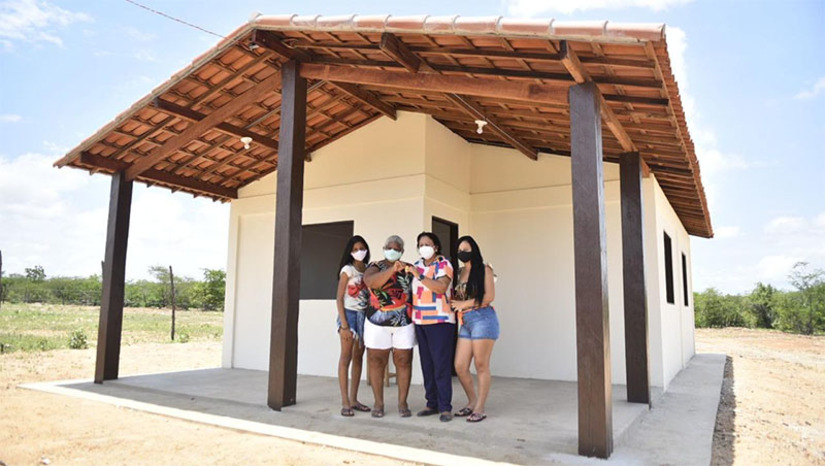 Imagem 1 -  Governo do RN entrega primeiras casas e lotes de terra da Agrovila Jucurutu. A entrega feita aos moradores de Carnaúba Torta, dá início à relocação de famílias que vivem em áreas inundáveis da Barragem Oiticica, principal obra hídrica do Rio Grande do Norte, que o governo do Estado está construindo na Bacia do Piranhas/Açu. Nesta sexta-feira (18) foram entregues dezesseis das 37 casas e lotes de terra da Agrovila. A transferência representa o começo de uma nova vida para 56 pessoas, garantindo condições dignas de moradia, com acesso aos serviços de água tratada, energia elétrica, terra para o plantio e segurança alimentar dos trabalhadores. 
