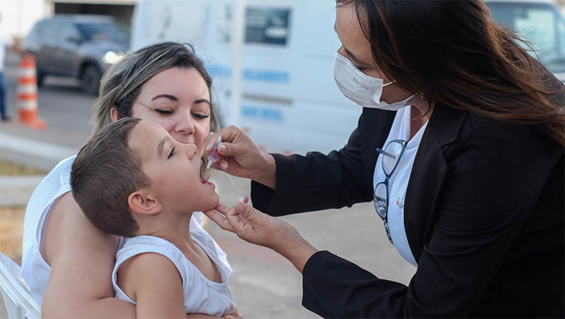 Imagem 1 - “Nós, pais, devemos assumir essa responsabilidade, trazer nossos filhos”. Mãe do pequeno Humberto Guedes, de 3 anos, a professora Zildenice Guedes foi a primeira a chegar ao ponto de vacinação contra a poliomielite, instalada pela Secretaria de Saúde de Mossoró, na Praça de Eventos, na tarde desta quinta-feira (6). A iniciativa foi mais uma estratégia da saúde municipal para facilitar o acesso da população ao imunizante que previne contra a doença que causa paralisia infantil. “É uma vacina muito importante e necessária, uma vez que estamos em alerta quanto à pólio. A vacina tem um caráter preventivo. Esse trabalho realizado aqui tem a finalidade também de educar e sensibilizar outras pessoas, outros pais, mães”, disse a professora. Imagem 1 - “Nós, pais, devemos assumir essa responsabilidade, trazer nossos filhos”. Mãe do pequeno Humberto Guedes, de 3 anos, a professora Zildenice Guedes foi a primeira a chegar ao ponto de vacinação contra a poliomielite, instalada pela Secretaria de Saúde de Mossoró, na Praça de Eventos, na tarde desta quinta-feira (6). A iniciativa foi mais uma estratégia da saúde municipal para facilitar o acesso da população ao imunizante que previne contra a doença que causa paralisia infantil. “É uma vacina muito importante e necessária, uma vez que estamos em alerta quanto à pólio. A vacina tem um caráter preventivo. Esse trabalho realizado aqui tem a finalidade também de educar e sensibilizar outras pessoas, outros pais, mães”, disse a professora.