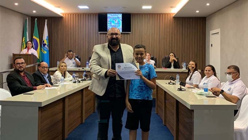 Imagem 1 - O projeto Câmara Mirim é uma iniciativa da Câmara Municipal de Grossos, através do mandato do Vereador Dauster Renard, com a apoio do TRE/RN, que disponibilizou equipamentos e servidores, e da Prefeitura de Grossos, por meio das equipes das escolas participantes. A apuração dos votos foi na Câmara Municipal de Grossos, durante uma sessão solene, com a presença de vereadores, candidatos, Familiares, o vereador da cidade de Rafael Fernandes, Vinicius Oliveira, representantes das escolas, a Prefeita de Grossos, Cinthia Sonale e a servidora do TER Andressa Castro, da Escola Judiciária. Nove candidatos foram eleitos. E outros nove ficaram na suplência. Na sequência da apuração dos votos, os eleitos foram diplomados. Imagem 1 - O projeto Câmara Mirim é uma iniciativa da Câmara Municipal de Grossos, através do mandato do Vereador Dauster Renard, com a apoio do TRE/RN, que disponibilizou equipamentos e servidores, e da Prefeitura de Grossos, por meio das equipes das escolas participantes. A apuração dos votos foi na Câmara Municipal de Grossos, durante uma sessão solene, com a presença de vereadores, candidatos, Familiares, o vereador da cidade de Rafael Fernandes, Vinicius Oliveira, representantes das escolas, a Prefeita de Grossos, Cinthia Sonale e a servidora do TER Andressa Castro, da Escola Judiciária. Nove candidatos foram eleitos. E outros nove ficaram na suplência. Na sequência da apuração dos votos, os eleitos foram diplomados.