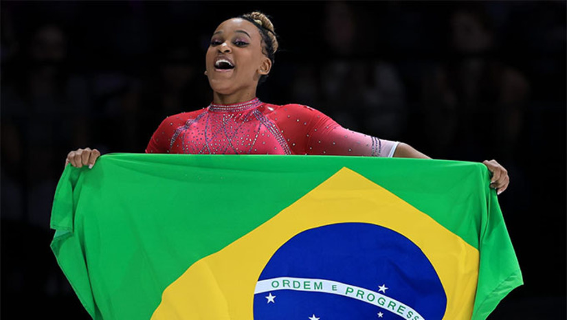 Imagem 1 -  A Rainha da Ginástica Brasileira fez, neste sábado, algo que ninguém conseguiu até agora no Mundial de Ginástica Artística da Antuérpia, na Bélgica: desbancar o fenômeno do esporte, Simone Biles. Rebeca Andrade conseguiu o ouro no salto sobre a mesa ao obter a média 14.750. A norte-americana, que sofreu uma queda em um de seus saltos, o Biles 2, registrou 14.549. A sul-coreana Yeo Seojeong (14.416) completou o pódio.   A ginasta de Guarulhos foi a última atleta a saltar. Na primeira rodada, executou um Cheng muito preciso, o que lhe valeu a nota 15.000. Depois, a brasileira mostrou um Yurchenko com dupla pirueta, que recebeu 14.500 pontos. 