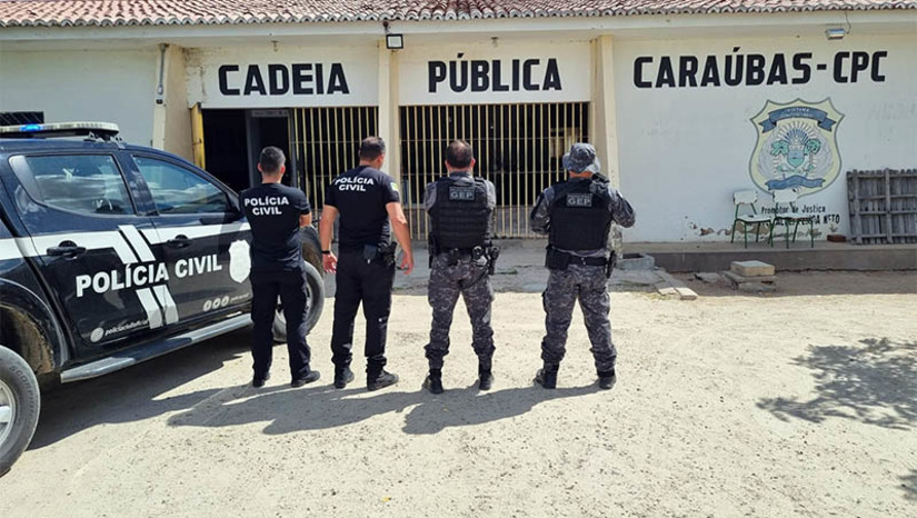 Imagem 1 - PC prende integrantes de organização criminosa que planejava morte de diretor da cadeia pública de Caraúbas. A ação, realizada nesta quarta-feira (11), está inserida no âmbito da "Operação Paz". Ao todo, no decorrer das diligências, foram cumpridos seis mandados de prisão temporária e mandados de busca e apreensão. De acordo com as investigações, iniciadas a partir de relatórios de inteligência, os integrantes de uma organização criminosa – alguns presos e outros não – estariam insatisfeitos com o regime disciplinar da unidade prisional. Por isso, planejavam o homicídio do diretor. Algumas ordens eram repassadas por meio de familiares que realizavam visitas aos presos. O delegado de Caraúbas, Gabriel Napoli, que comandou as investigações, informou que as investigações continuam e outras diligências ainda serão realizadas. Imagem 1 - PC prende integrantes de organização criminosa que planejava morte de diretor da cadeia pública de Caraúbas. A ação, realizada nesta quarta-feira (11), está inserida no âmbito da "Operação Paz". Ao todo, no decorrer das diligências, foram cumpridos seis mandados de prisão temporária e mandados de busca e apreensão. De acordo com as investigações, iniciadas a partir de relatórios de inteligência, os integrantes de uma organização criminosa – alguns presos e outros não – estariam insatisfeitos com o regime disciplinar da unidade prisional. Por isso, planejavam o homicídio do diretor. Algumas ordens eram repassadas por meio de familiares que realizavam visitas aos presos. O delegado de Caraúbas, Gabriel Napoli, que comandou as investigações, informou que as investigações continuam e outras diligências ainda serão realizadas.