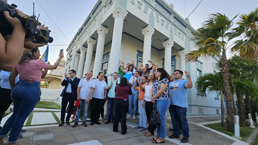 Imagem 1 -  Os projetos de Lei instituindo o PCCR dos servidores gerais e dos assistentes sociais foram sancionado na tarde desta sexta-feira, 27, no Salão dos Grandes atos da Palácio da Resistência. O prefeito Allyson Bezerra destacou o diálogo respeitoso. A servidora fala em avanço histórico e agradece ao gestor. O psicólogo Alcedir Gabriel destaca que se trata de um passo importante da gestão. Os planos entram vigora agora em novembro e em dezembro já terá o reajuste nos salários dos servidores.
