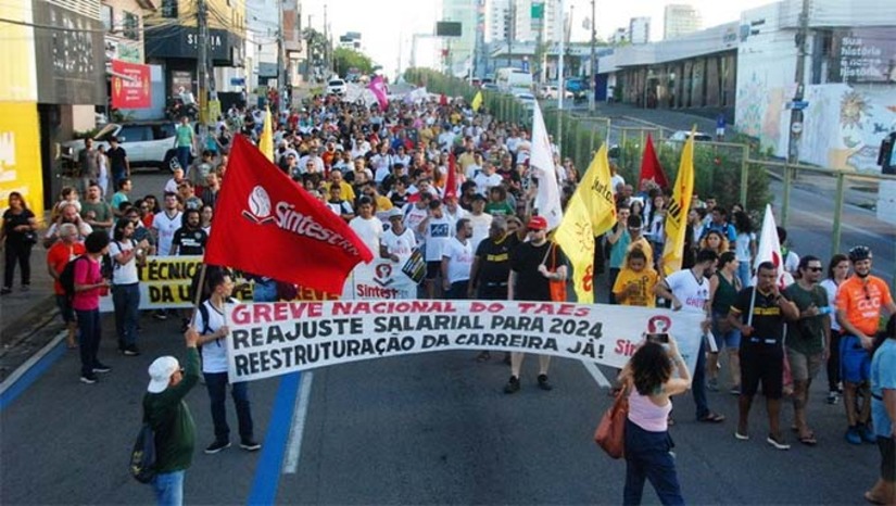Imagem 1 - Servidores técnico-administrativos da UFRN e da UFERSA vão paralisar as atividades nesta segunda-feira, 5 de maio, cobrando do governo federal o cumprimento integral do Acordo de Greve de 2024, que ainda tem nove pontos pendentes. A paralisação, orientada pela FASUBRA Sindical, será organizada no estado pelo SINTEST-RN. Na UFRN, a greve segue desde 1º de abril, enquanto na UFERSA, além da paralisação, foi decretado estado de greve em assembleia no dia 30 de abril. Até agora, o único avanço foi a efetivação do reajuste de 9%, pago em abril com retroativo, e a atualização da tabela de remuneração do PCCTAE. O prazo para que o governo atenda às demais demandas termina em 31 de maio. Imagem 1 - Servidores técnico-administrativos da UFRN e da UFERSA vão paralisar as atividades nesta segunda-feira, 5 de maio, cobrando do governo federal o cumprimento integral do Acordo de Greve de 2024, que ainda tem nove pontos pendentes. A paralisação, orientada pela FASUBRA Sindical, será organizada no estado pelo SINTEST-RN. Na UFRN, a greve segue desde 1º de abril, enquanto na UFERSA, além da paralisação, foi decretado estado de greve em assembleia no dia 30 de abril. Até agora, o único avanço foi a efetivação do reajuste de 9%, pago em abril com retroativo, e a atualização da tabela de remuneração do PCCTAE. O prazo para que o governo atenda às demais demandas termina em 31 de maio.