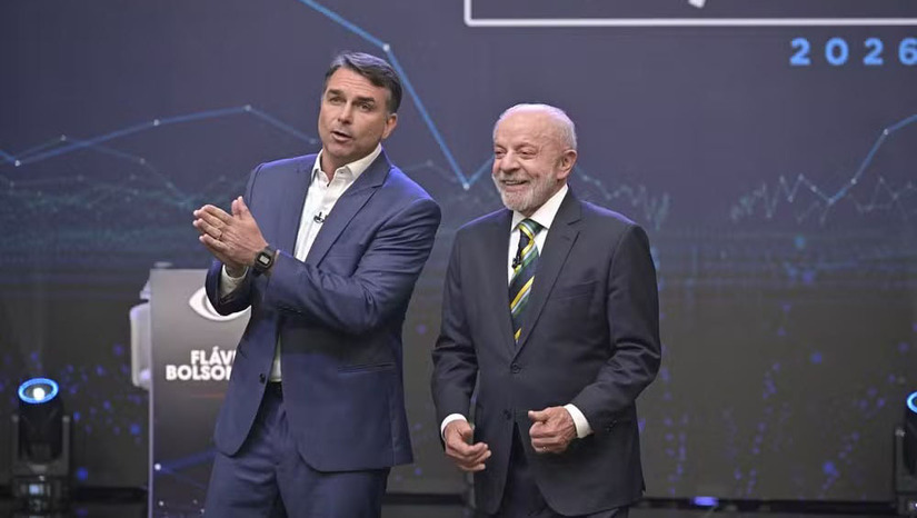   Confronto caótico na Band entre Lula e Flávio Bolsonaro é classificado como estéril por analistas. Análises apontam que espetáculo caótico priorizou ataques pessoais em detrimento de propostas. Veículos de comunicação destacaram o uso de encenações provocativas no palco do estúdio. Agências de checagem desmentiram dados falsos do senador sobre economia e gastos de viagens.